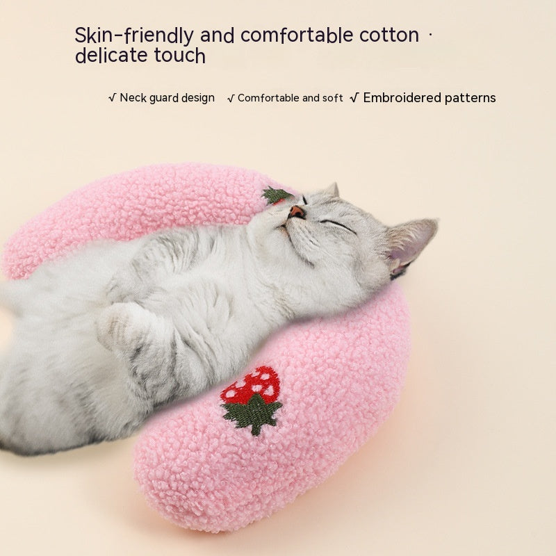 Small dog sleeping with a pink plush neck support pillow for pets.